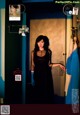 A woman in a black dress standing in front of a door.