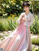 A woman in a pink and blue dress standing in a garden.