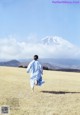 A woman in a blue dress running across a field.