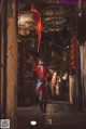 A woman in a red coat walking down a street at night.