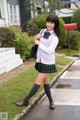 A woman in a school uniform is walking down the street.