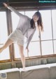 A woman standing on top of a couch in front of a window.