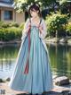 A woman in a blue dress standing in front of a pond.